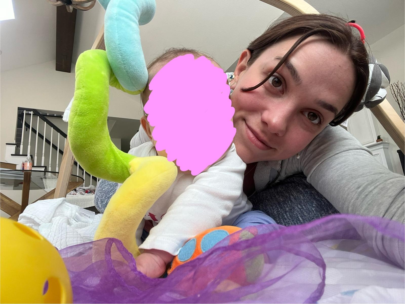 A second, nearly identical frame of Aurora Carlin Martini beside the same baby, whose face is again covered by a pink mark.