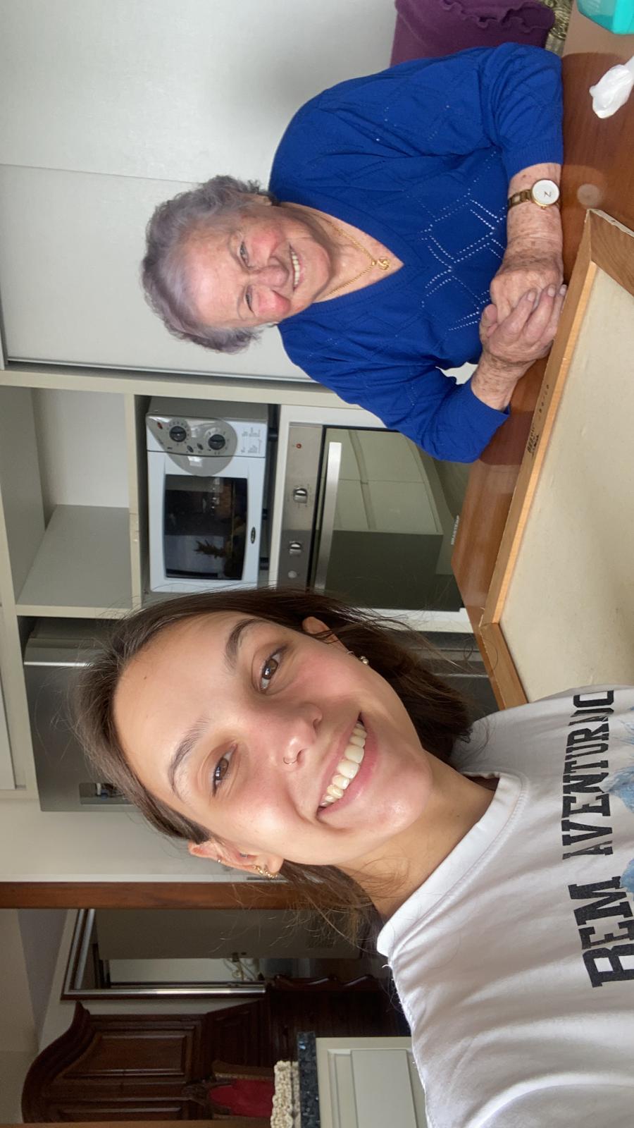 A selfie of Aurora Carlin Martini and an older woman in a blue jumper in a kitchen. The frame is stored rotated a quarter turn, so both appear lying on their side.