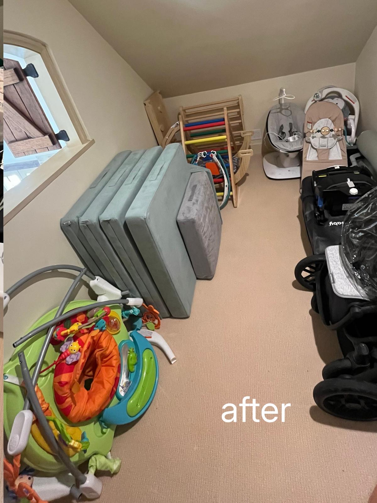 The same storage room with the play mats stacked upright against one wall and the baby equipment lined along the other, the floor clear between them.
